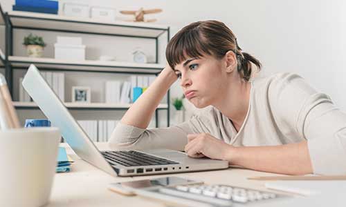 girl at desk hunched over with computer bad posture frustrated