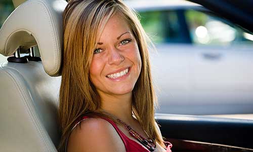 girl smiling leaning on headrest inside car